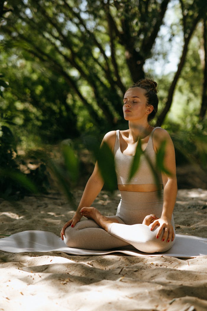 our-experience A woman meditating peacefully in a sunlit forest, embodying relaxation and mindfulness.