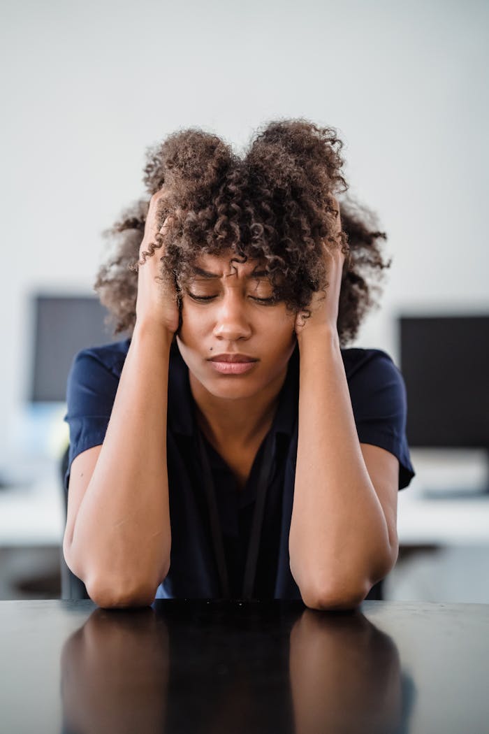 why-choose-us Woman in office setting expresses stress, seated at desk with hands in hair. Perfect for workplace stress concept.
