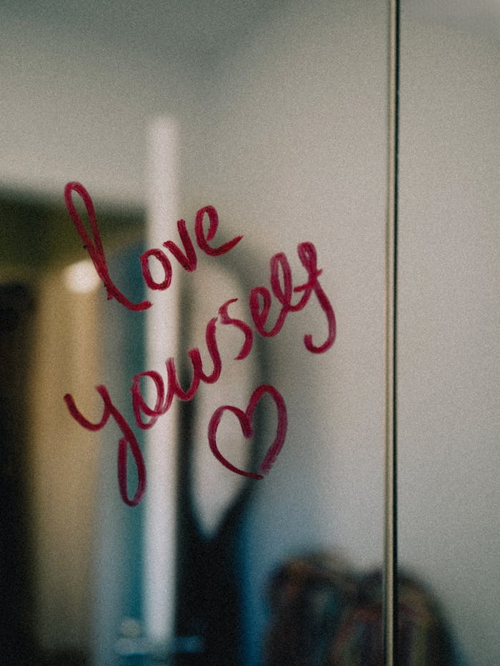 our-services-3 Positive affirmation written on a mirror in red lipstick: Love Yourself.